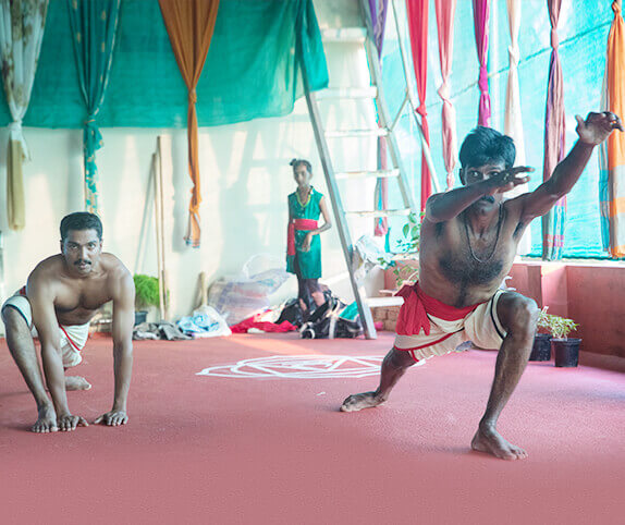 Kalaripayattu students practicing traditional martial arts poses in a training hall