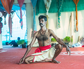 Kalaripayattu practitioner sitting in a traditional pose inside a training hall