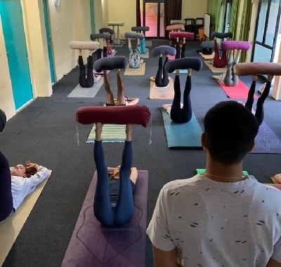Yoga students practicing supported shoulder stands using bolsters in a guided class for relaxation and alignment