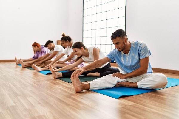Yoga Class Practicing Seated Forward Bend Stretch in Rishikul Togshala Group of people practicing seated forward bends