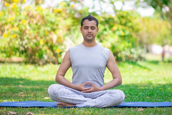 A man sitting cross-legged practicing mantra meditation
